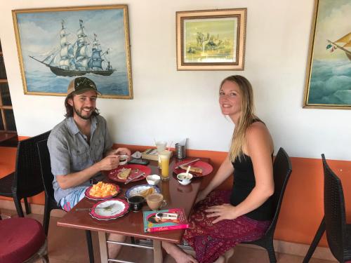 un hombre y una mujer sentados en una mesa con comida en Sajhome Fortkochi, Kochi, Kerala, inda, en Kochi