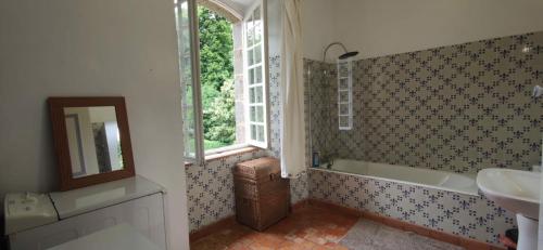 een badkamer met een bad, een wastafel en een spiegel bij Maison de Maître - chambre chez particulier in Landéan