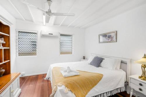 a white bedroom with a bed with a wooden floor at Inner City Serenity in Cairns