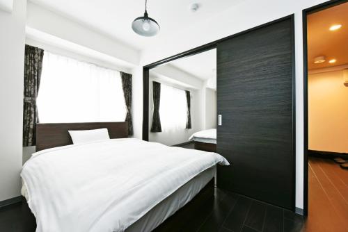 a bedroom with a white bed and a large window at Sun Court Hondori Garden Hills in Tsukisappu