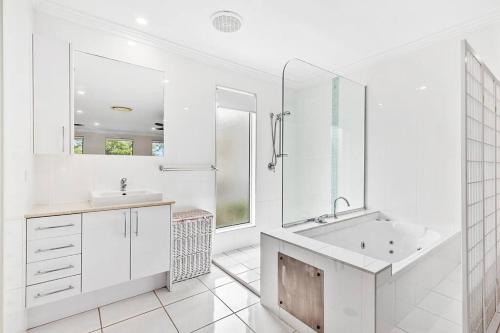 a white bathroom with a tub and a sink at Smooth Sailing -Modern 2 bedroom apartment! in Bellara