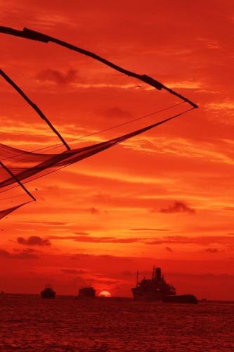 a sunset over the ocean with a ship in the distance at Sajhome Fortkochi, Kochi, Kerala, inda in Cochin