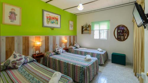 two beds in a room with green walls at El Castillejo Alpandeire by Ruralidays in Alpandeire