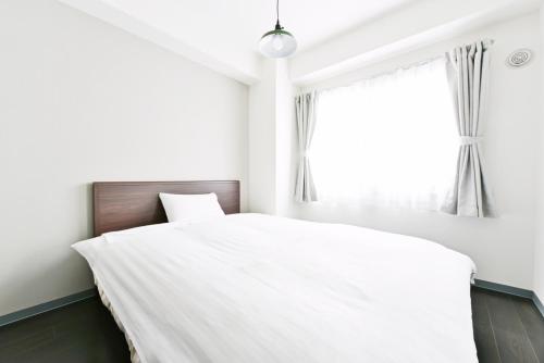 a bedroom with a white bed and a window at Sun Court Hondori Garden Hills in Tsukisappu
