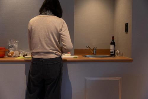 a person standing at a sink in a kitchen at Higashikawa Asahidake Onsen Hotel Bear Monte in Higashikawa