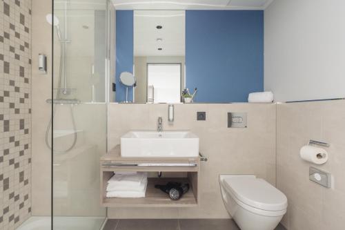 uma casa de banho com um lavatório, um WC e um chuveiro em Select Hotel Augsburg em Neusäß