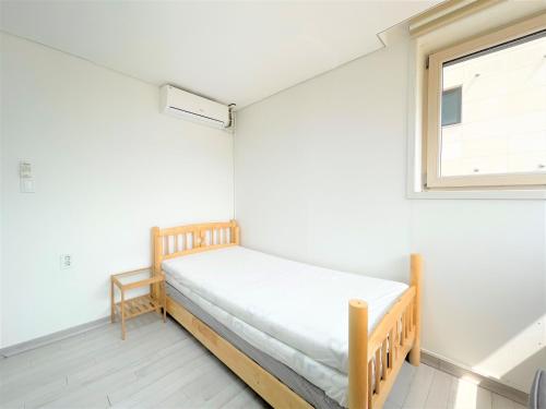 a small bedroom with a bed and a window at Koin Guesthouse Incheon airport in Incheon