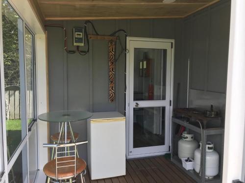 a porch with a table and a door to a kitchen at Farmland retreat in Tokoroa