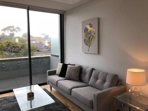 a living room with a couch and a glass table at Beautiful Apartment in Chatswood in Sydney