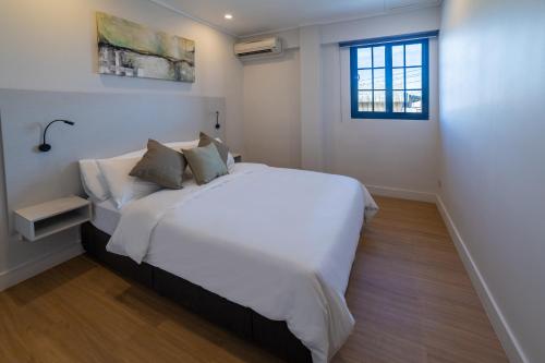 uma grande cama branca num quarto com uma janela em Toorak Central em Suva