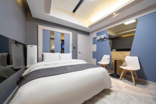 um quarto com uma cama grande e 2 cadeiras brancas em The Nox Hotel em Suwon