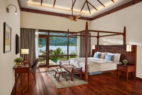 Taj Wayanad Resort & Spa, Kerala في واياناد: غرفة نوم بسرير مظلة ونافذة كبيرة
