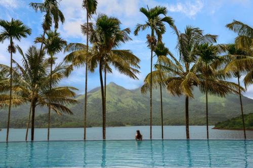 uma mulher parada numa piscina com palmeiras em Taj Wayanad Resort & Spa, Kerala em Wayanad