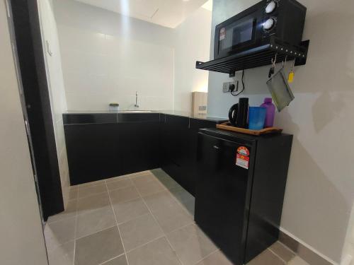 a kitchen with a black refrigerator and a microwave at Alish Studio Apartment with Pool, Netflix, Wifi in Gua Musang