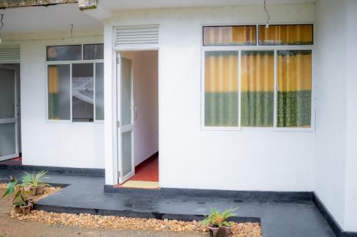 a white house with two doors and plants at Rainforest Holiday Inn in Deniyaya