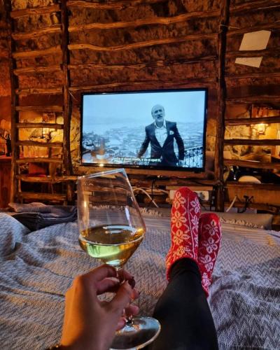 a person sitting on a bed with a glass of wine at Zemljane kućice Kreševo in Kreševo