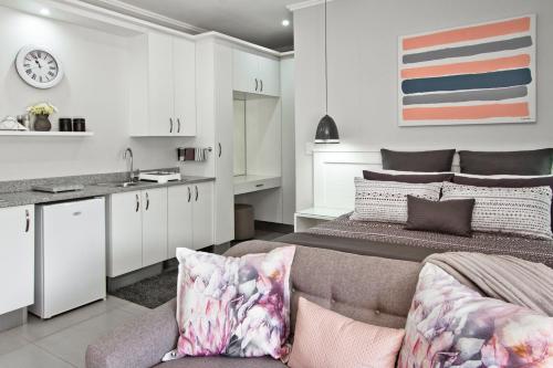 um quarto com uma cama, um sofá e uma cozinha em Kent Manor Guest Suites em Joanesburgo