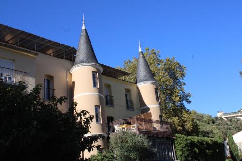 a castle with two towers on the side of a building at Appart'Hotel Castel Emeraude, Charme et Caractère in Amélie-les-Bains-Palalda