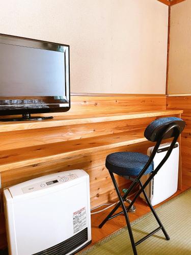 a chair sitting in front of a tv and a televisionictericter at Hakuba Pension & Log Hotel Meteor in Hakuba