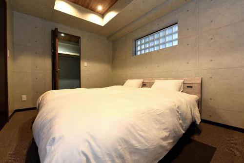 a bedroom with a large white bed with a window at Hills Garden 本通 in Tsukisappu