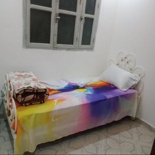 a bed with a rainbow colored comforter in a room at غرفة فردية خاصة للاناث in Bel Aroussi