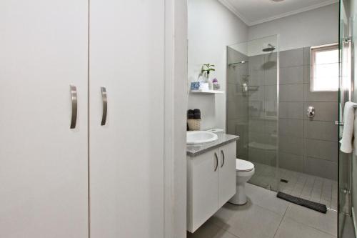 a white bathroom with a toilet and a sink at Kent Manor Guest Suites in Johannesburg