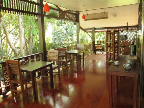 un restaurant avec des tables en bois, des chaises et des arbres dans l'établissement Happiness Resort Sukhothai, à Sukhothaï