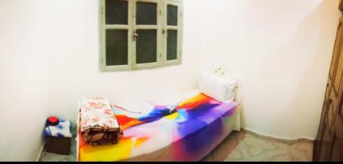 a bedroom with a rainbow bed and a window at غرفة فردية خاصة للاناث in Bel Aroussi