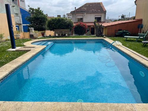 a blue swimming pool with a house in the background at Apartamento con piscina privada in Vigo