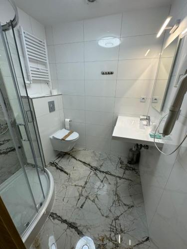 a white bathroom with a sink and a toilet at Hotel Kresowianka in Konin