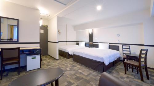 a hotel room with two beds and a table and chairs at Toyoko Inn HOSPITAL INN Dokkyo Medical University in Mibu