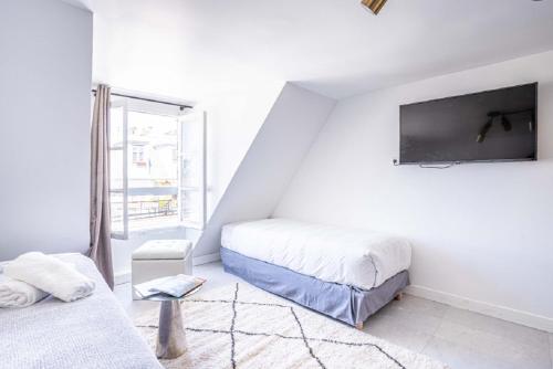 パリにある145 - Urban Pretty Studio in Center of Parisの白い部屋で、ベッド2台、薄型テレビが備わります。