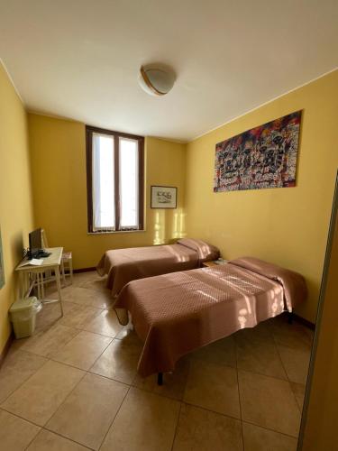 um quarto com duas camas e uma mesa e uma janela em B&B In Liberty Style em Settimo Milanese