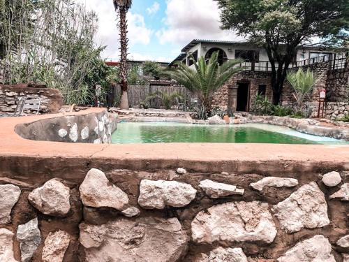 a swimming pool in a yard with a stone wall at Nkisi Guesthouse in Kang