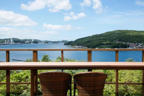 two chairs sitting on a balcony overlooking the water at Kisara Bettei TOKI in Toba