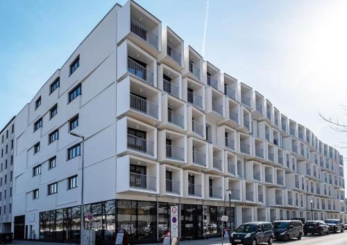 a white building with cars parked in front of it at MyRoom Apartment in Munich in Munich