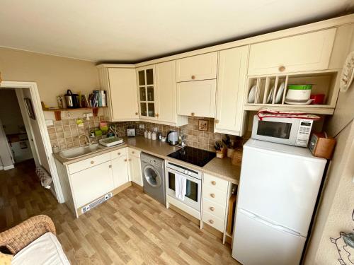 a kitchen with white cabinets and a white refrigerator at Cosy boutique apartment in colourful Bristol in Bristol