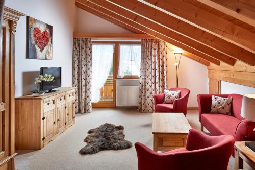 sala de estar con sillas rojas y TV en Landhaus Marie, en Schwangau