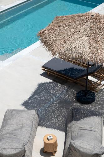 a straw umbrella and chairs next to a swimming pool at Drios Luxury Studios in Drios