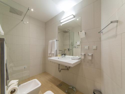 a white bathroom with a sink and a mirror at Hotel TQ Plaza in Budva