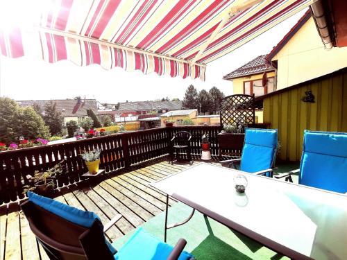 eine Terrasse mit Stühlen und Tischen auf einer Holzterrasse in der Unterkunft Ferienwohnung Martina in Hasselfelde