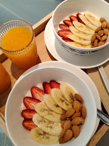 two bowls of fruit and nuts and a bowl of orange juice at Nidhra Boutique Hotel Bangkok Sukhumvit in Bangkok