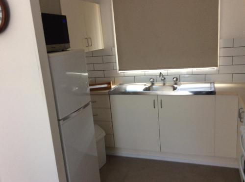 a kitchen with a sink and a white refrigerator at Cozy Home Style Accommodation in Marong