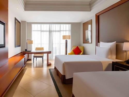 a hotel room with two beds and a table at Pullman Haikou in Haikou