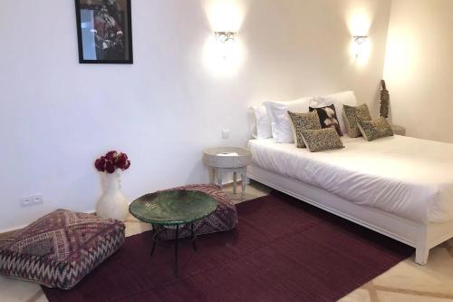 uma sala de estar com uma cama branca e uma mesa em RIAD HAWWA JANNA - Privatif em Marrakech