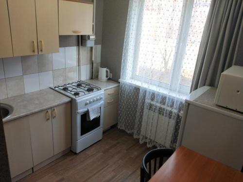 a small kitchen with a stove and a window at Абая in Petropavlovsk