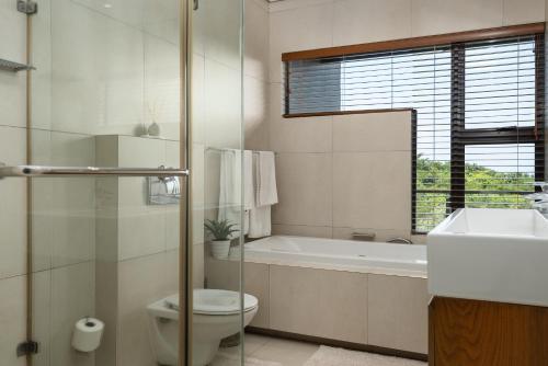 a bathroom with a toilet and a tub and a sink at Luxury 3 Bed Villa- Zimbali Coastal Resort Retreat in Ballito