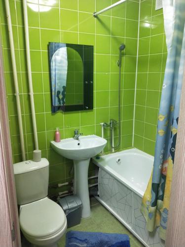 Baño de azulejos verdes con aseo y lavamanos en Абая en Petropavlovsk
