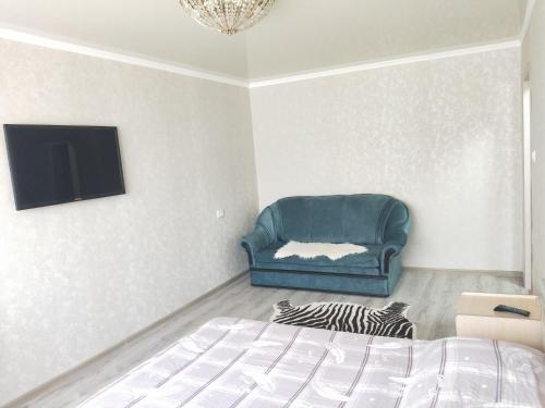 1 dormitorio con 1 cama y 1 silla azul en Абая en Petropavlovsk