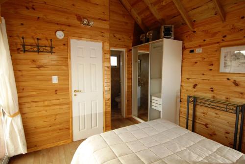 a bedroom with a bed in a room with wooden walls at Cabañas Rincones del Sur in Trevelin